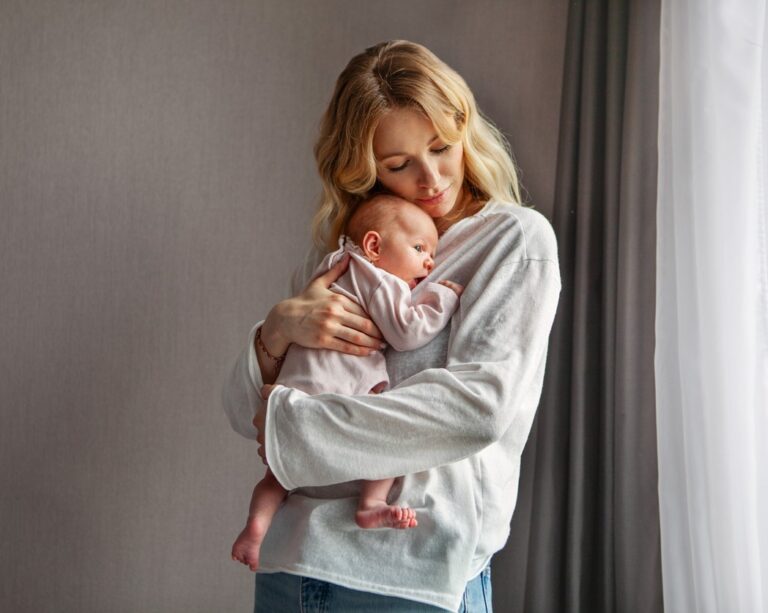 Een vrouw houdt een baby tegen haar borst en kijkt naar het kind.