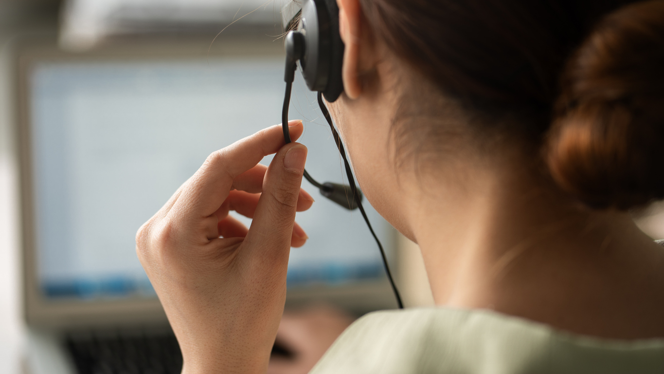 Medewerker met headset achter een computer tijdens een gesprek.
